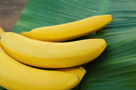 Delicious bananas and green leaf on wooden table, closeupの写真素材