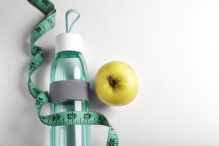 Measuring tape, apple and bottle of water on white background, flat lay with space for text. weight control conceptの写真素材