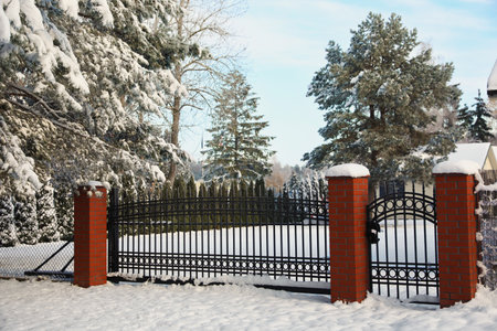 Winter landscape with beautiful snowy park behind a fence in the morning