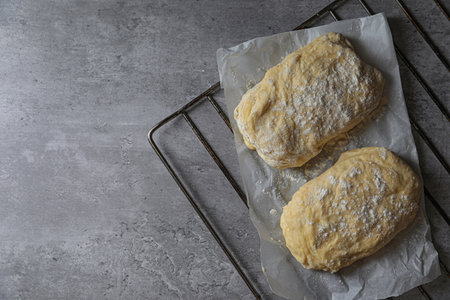 Raw dough and flour on gray table, top view with space for text. Cooking ciabatta