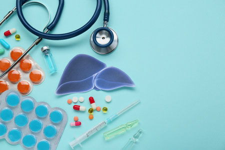 Paper liver and medical supplies on turquoise background, flat lay with space for text. Hepatitis...