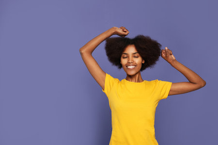 Portrait of smiling African American woman on purple background. Space for text