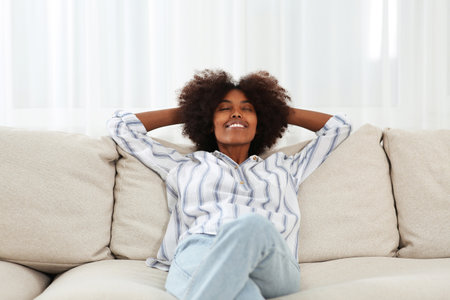 Smiling African American woman on sofa at homeの写真素材