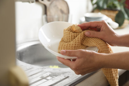 Woman wiping plate with towel in kitchen , closeupの写真素材