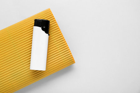 Stylish small pocket lighter with yellow corrugated fiberboard on white background, top view. Space for textの写真素材