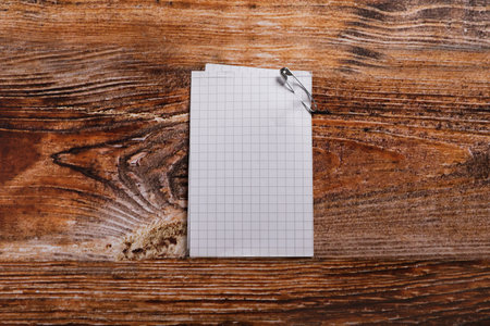Paper sheets with attached safety pin on wooden table, top view. Space for textの写真素材