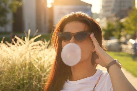 Beautiful woman blowing gum outdoors, space for textの写真素材