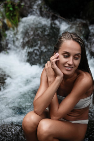 Beautiful young woman in light blue bikini near mountain stream outdoors. Space for textの写真素材