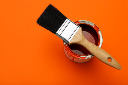 Can of orange paint and brush on color background, top view. Space for textの写真素材