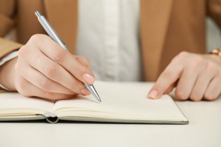 Woman writing in notebook at white table, closeupの写真素材