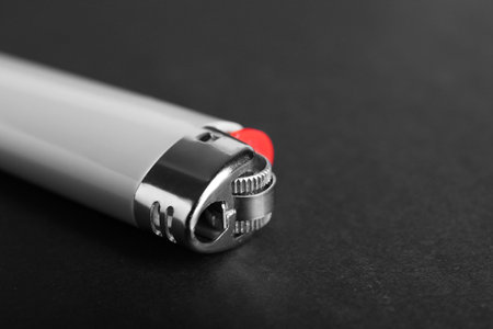 Stylish small pocket lighter on black background, closeup. Space for textの写真素材
