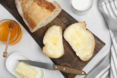 Sandwiches with butter, honey and milk on white table, flat layの写真素材