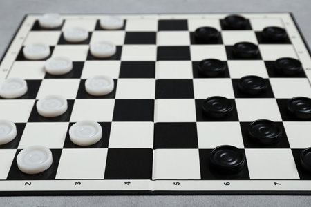 Checkerboard with game pieces on light gray table, closeupの写真素材