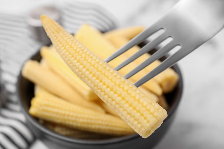 Pickled baby corn on fork at table, closeupの写真素材