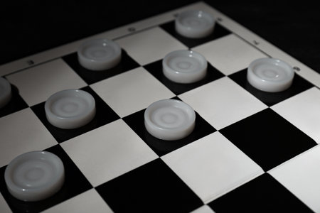 Checkerboard with game pieces on dark background, closeupの写真素材