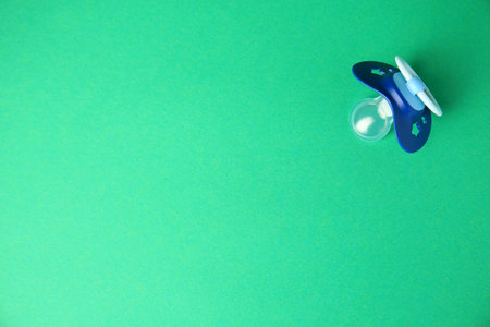 Blue baby pacifier on green background, top view. Space for textの写真素材