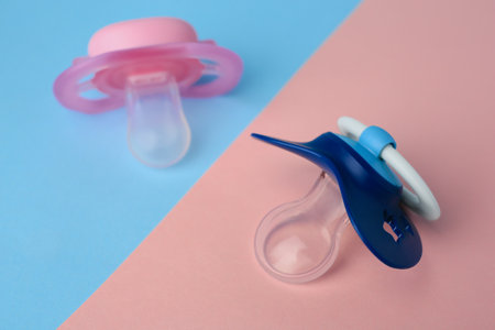 Different baby pacifiers on bright color background