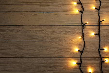 Glowing festive lights on wooden background, top view. Space for textの写真素材