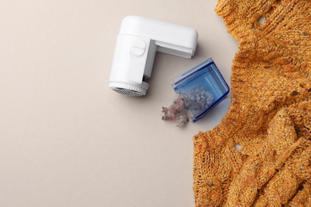 Modern fabric shaver with fuzz and knitted sweater on white background, flat lay. Space for textの写真素材