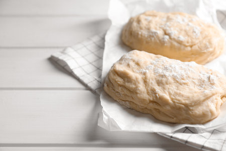 Raw dough and flour on white wooden table, space for text. Cooking ciabattaの写真素材