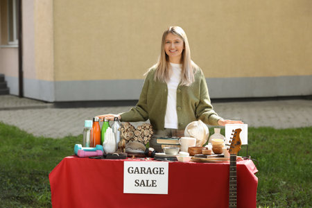 Woman selling different items on garage sale in yardの写真素材