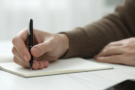 Man writing in notebook at white wooden table, closeupの写真素材