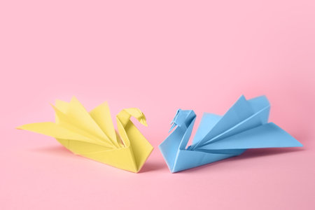 origami art. Beautiful paper swans on pink backgroundの写真素材