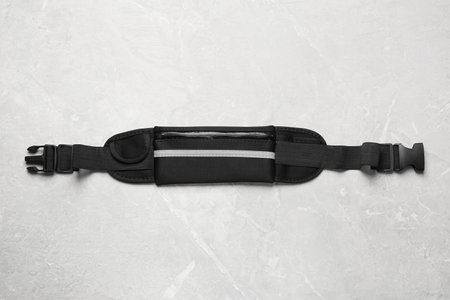 Stylish black waist bag on light gray table, top view