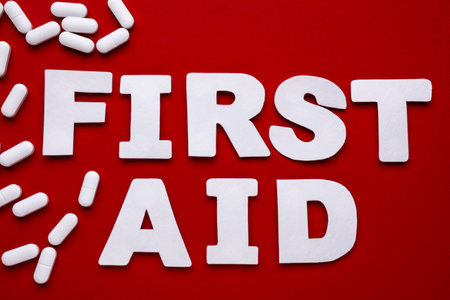Words First Aid made of white letters and pills on red background, flat layの写真素材