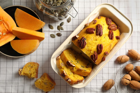 Delicious pumpkin bread with pecan nuts on tablecloth, flat layの写真素材