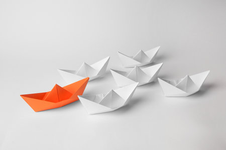 Group of paper boats following orange one on white background. leadership conceptの写真素材