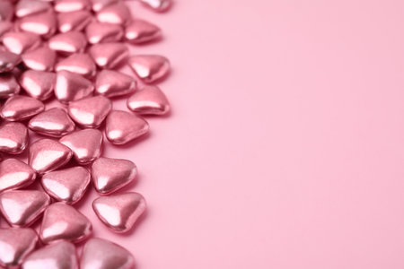 Many delicious heart shaped candies on pink background. Space for text