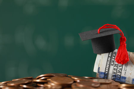 Scholarship concept. Graduation cap, coins and dollar banknotes against blurred background, closeup. Space for textの写真素材