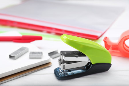 New bright stapler with stationery on white wooden tableの写真素材