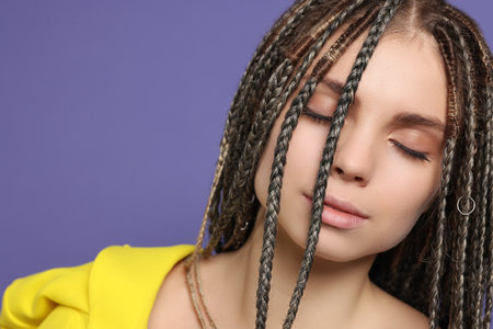 Beautiful woman with long african braids on purple background, closeup. Space for text