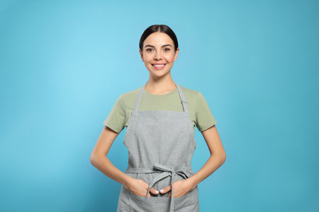 Young woman in gray apron on light blue background,の写真素材