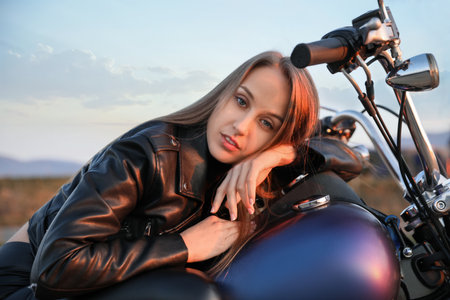 Beautiful young woman on motorcycle outdoors in the eveningの写真素材