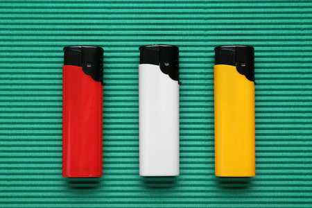 Stylish small pocket lighters on green corrugated fiberboard, flat layの写真素材