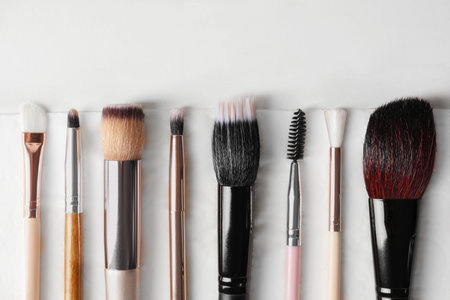 Set of different makeup brushes drying after cleaning on white table, flat lay. Space for textの写真素材