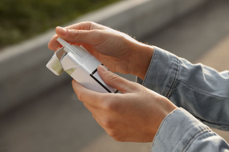 Woman taking cigarette out of pack outdoors, closeup