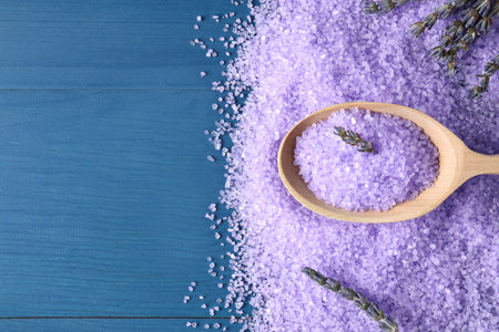 Spoon with lilac sea salt and lavender flowers on blue wooden table, flat lay. Space for textの写真素材