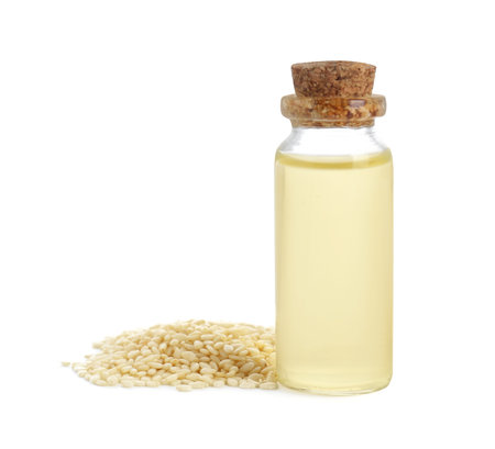 Glass bottle with fresh sesame oil and seeds isolated on whiteの写真素材