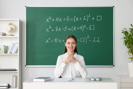 Young math's teacher giving lesson at table in classroom