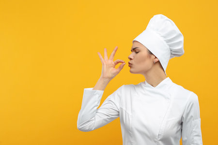 Female chef showing perfect sign on orange background. Space for textの写真素材