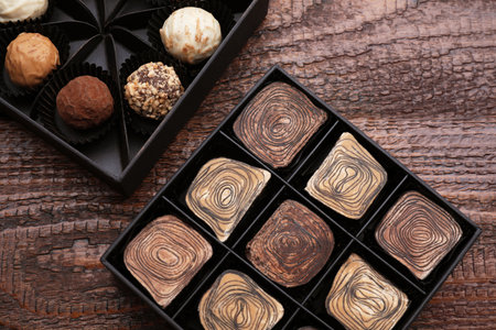 Boxes of tasty chocolate candies on wooden table, flat lay