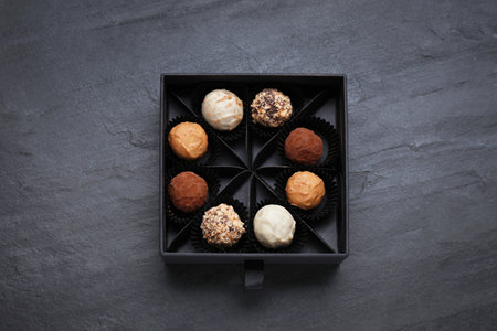 Box of tasty chocolate candies on black table, top viewの写真素材
