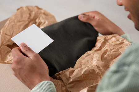 Young man holding greeting card near parcel with Christmas gift, closeupの写真素材
