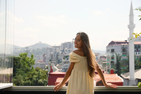 Beautiful young woman with long hair standing on balcony