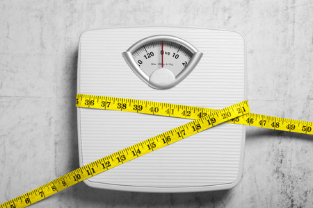 Scales and measuring tape on gray textured background, top view. weight loss concept