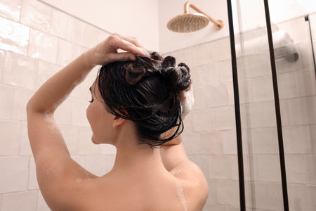 Woman washing hair while taking shower at home, back viewの写真素材